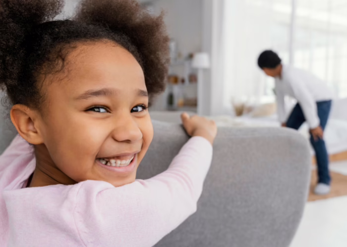 Criança sorrindo em casa com a família ao fundo